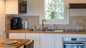 A kitchen with a built-in oven, a coffee maker, a sink, and a window with a view of trees. - Charming Duplex 500m from the port (Hyères)