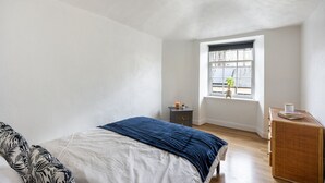 A bedroom with a bed, a window, a small table, and a dresser. - Stylish 1BR in Edinburgh New Town (Edinburgh)