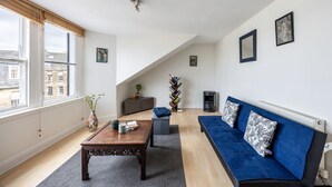 A modern living room with a sofa, coffee table, and a bookshelf. - Stylish 1BR in Edinburgh New Town (Edinburgh)