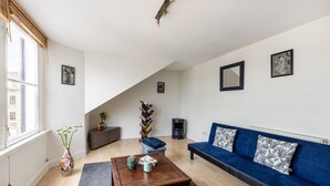 A living room with a sofa, coffee table, bookshelf, and a window with a view. - Stylish 1BR in Edinburgh New Town (Edinburgh)