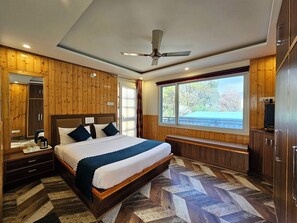 Ein Schlafzimmer mit Bett, Holzwänden, Deckenventilator, Fenster mit Aussicht und Fernseher.
