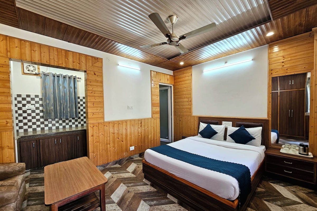 A room with a bed, a table, a wardrobe, and a ceiling fan.
