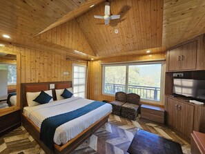 A wooden cabin bedroom with a bed, a TV, and a large window. - Seven Heaven (Kandaghat)