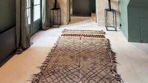 Een modern interieur met een groot raam, een kamerbreed tapijt en een keuken op de achtergrond.