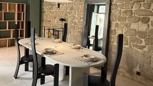 Een eetruimte met een stenen muur, een ronde tafel en moderne stoelen.
