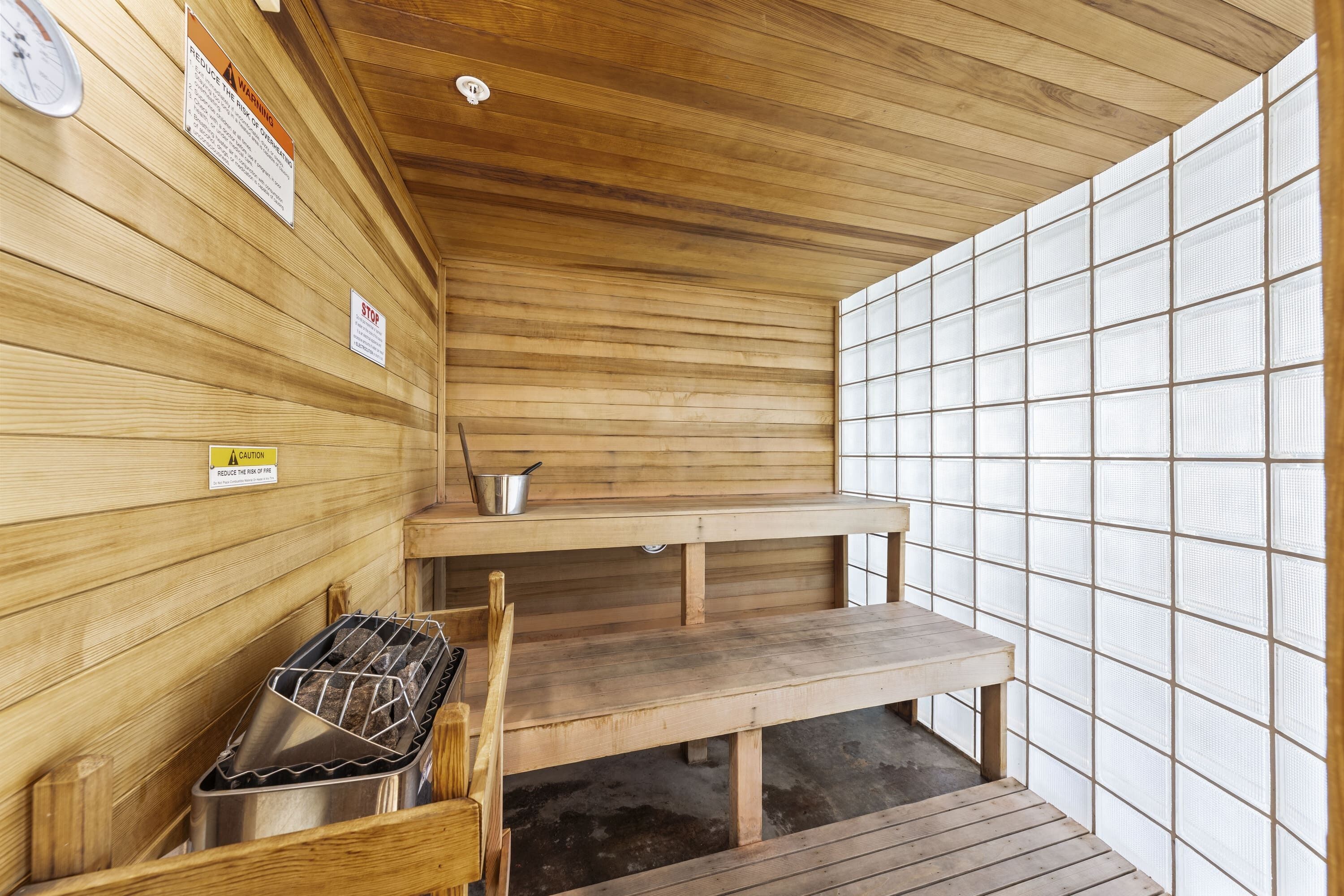 A sauna with wooden walls, a bench, and a metal container.