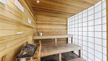 A sauna with wooden walls, a bench, and a metal container.