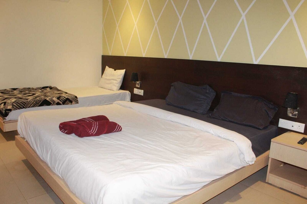 A hotel room with two beds, a wooden headboard, a wall-mounted light fixture, and a nightstand with a remote control.