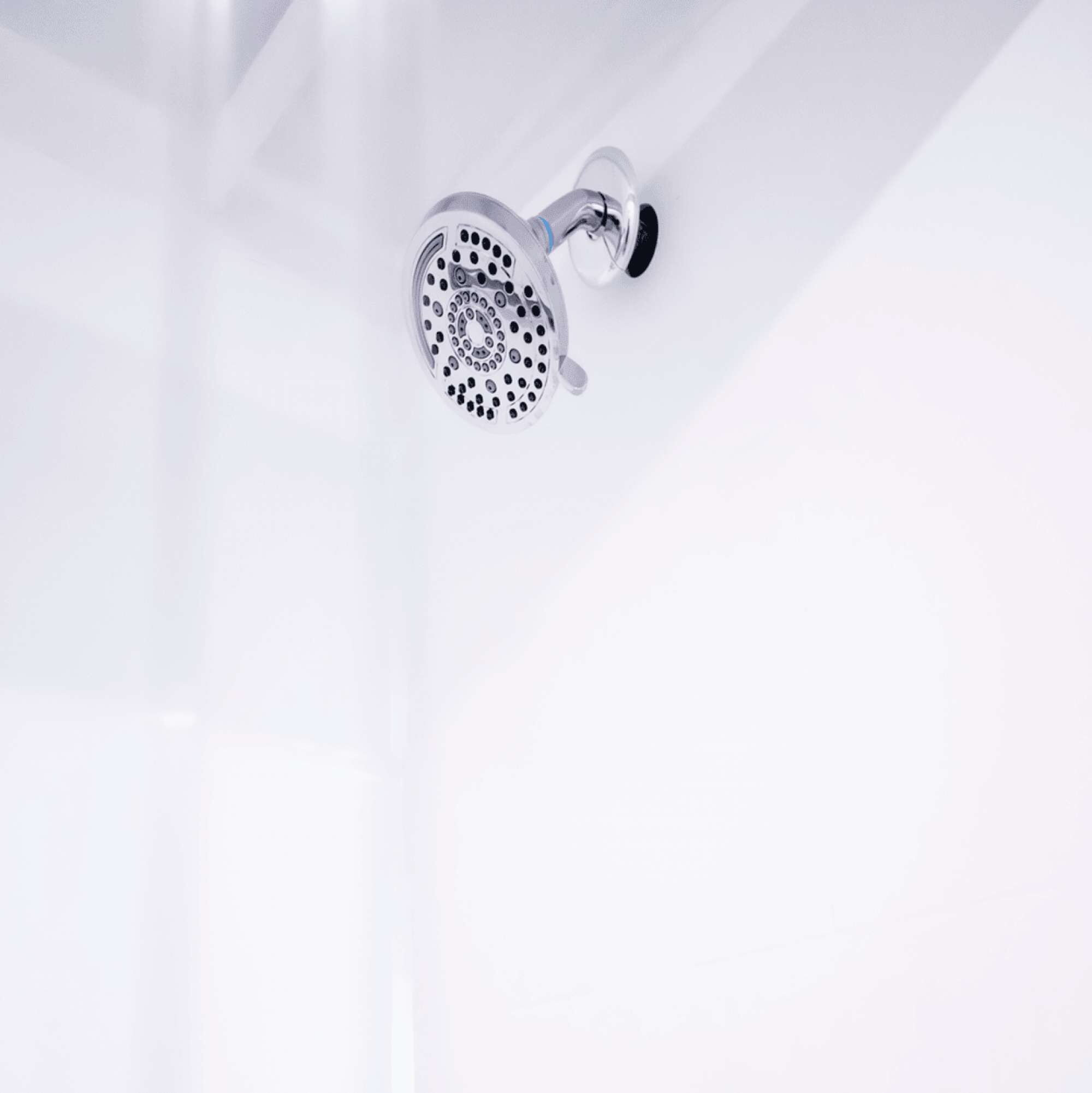 Un pommeau de douche moderne, de forme circulaire, fixé sur un mur blanc.