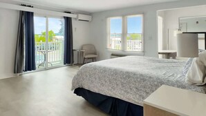 A hotel room with a bed, a chair, a desk, and a balcony with a view. - King + Sofa w/ Balcony + Free Breakfast & Parking (Rockland)