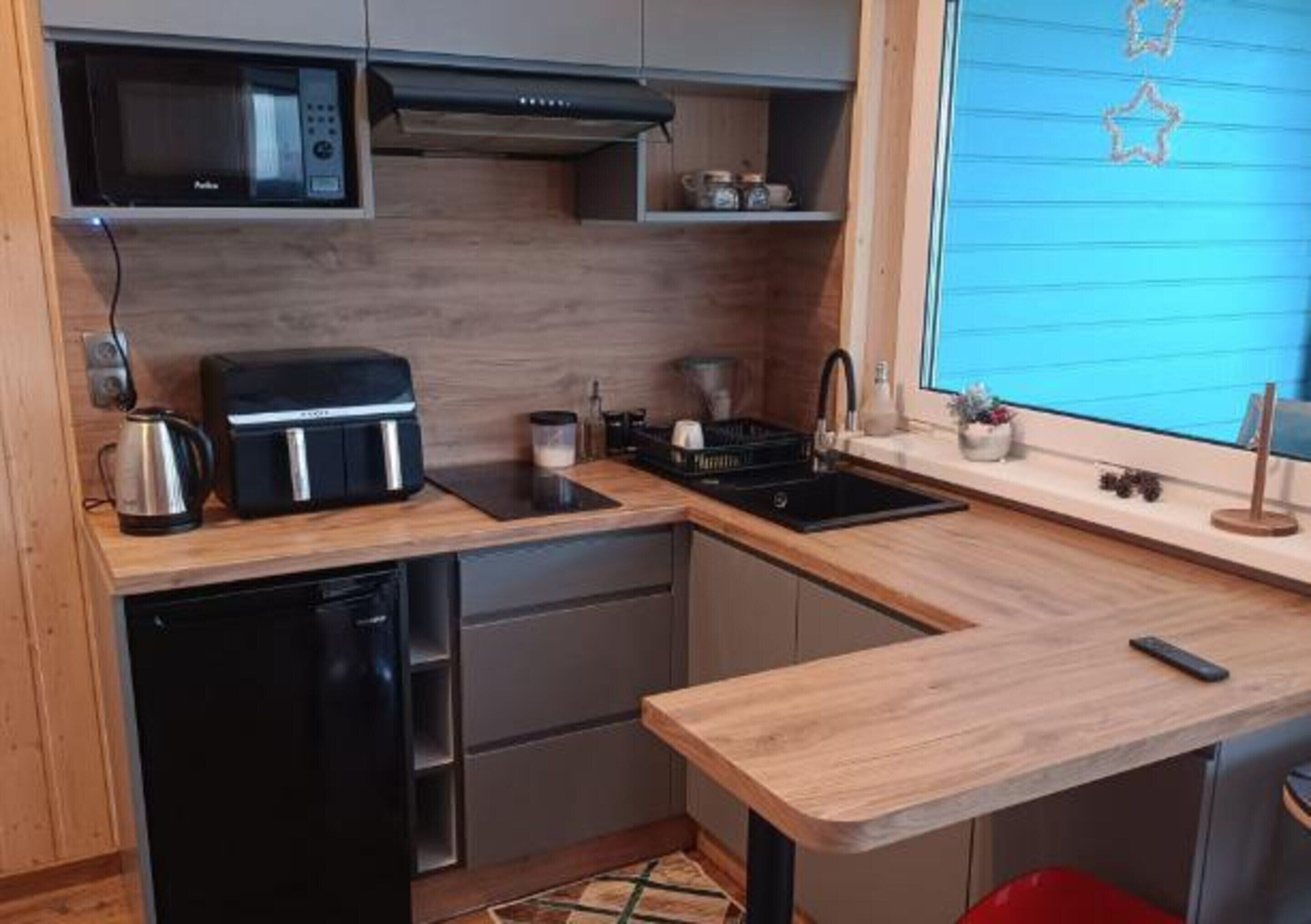 Una cocina compacta equipada con microondas, tostadora, fregadero y un refrigerador pequeño.
