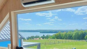 Una habitación con un ventanal que ofrece vistas a un lago y un bosque.