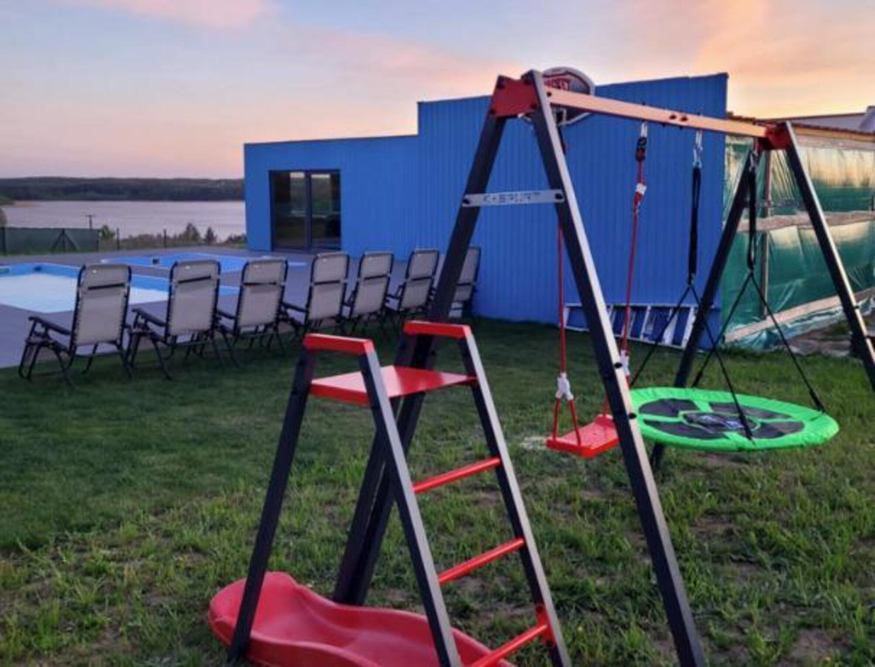 Un jardin avec une balançoire, un trampoline et une piscine.
