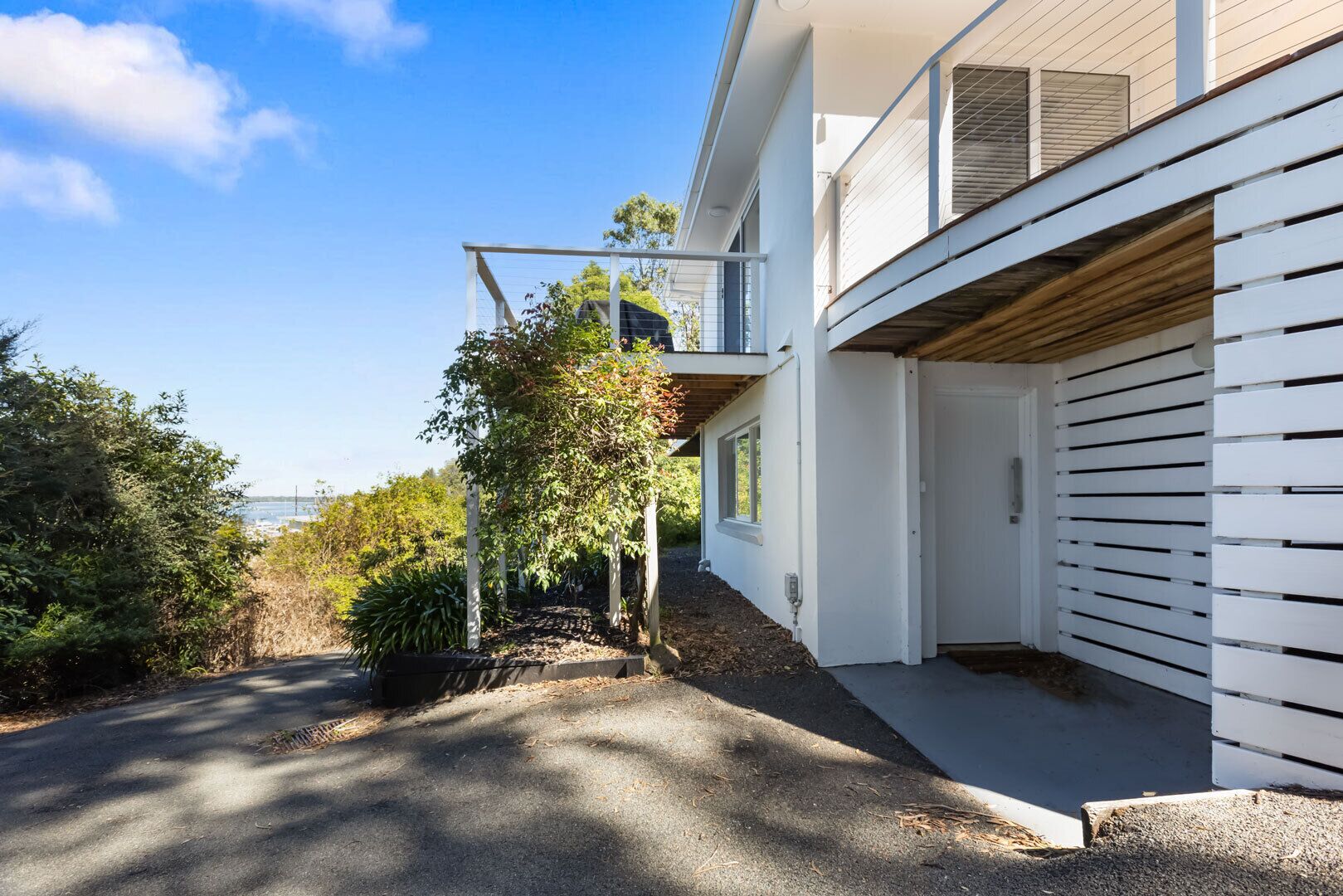 Ein modernes Haus mit überdachter Auffahrt, Garage und Balkon.