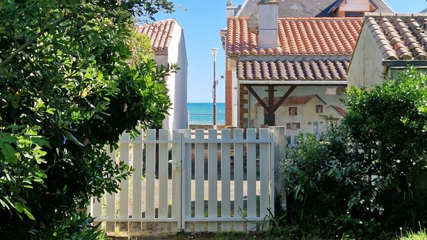 Ein Haus mit einem Ziegeldach, weißem Zaun und einem Rasen.