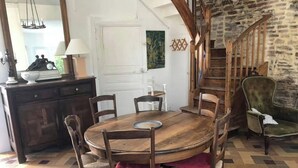 Ein Essbereich mit Holztisch, Stühlen, einer Kandelaber, einer Treppe und einer Steinwand.