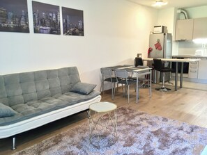 A modern living room with a grey sofa, a small round table, and a cityscape view.