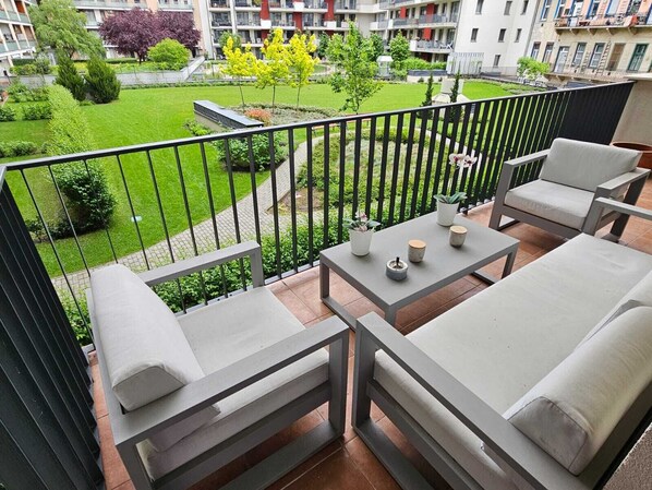 A balcony with a sofa, a small table, and potted plants.