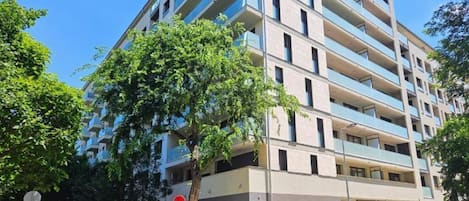 Un immeuble à plusieurs étages doté de balcons, d’un restaurant et de voitures garées.