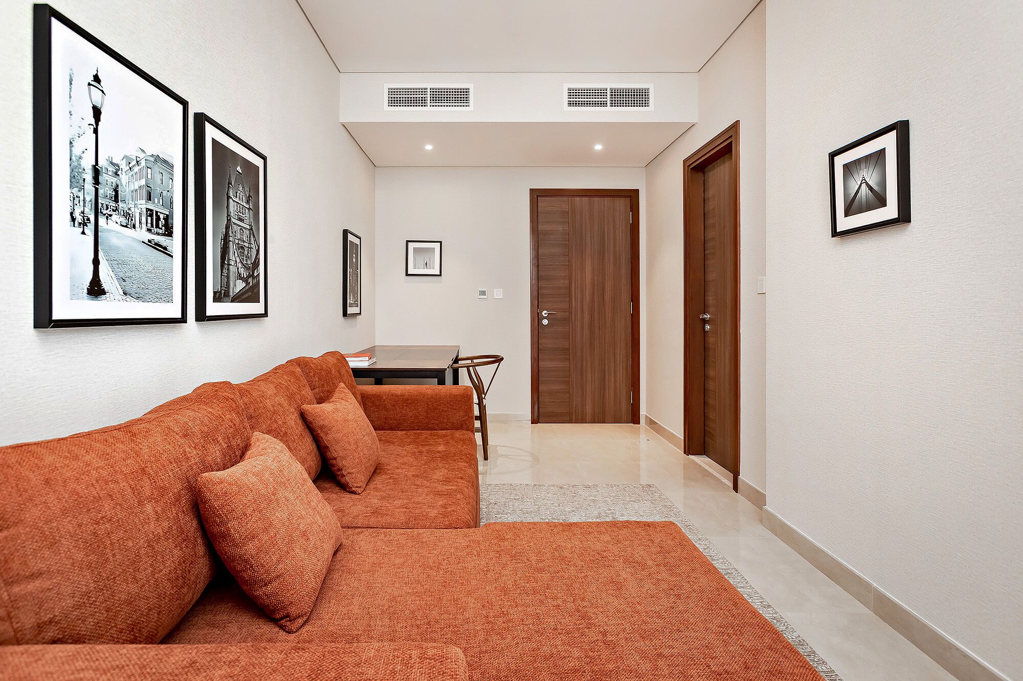 A hallway with a sofa, framed pictures, a wooden door, and a small table.