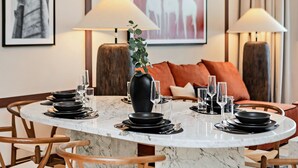 Un coin repas avec une table ronde dressée pour quatre personnes, entourée de chaises en bois.