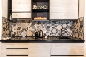 A kitchen with a black countertop, wooden cabinets, a coffee maker, a kettle, and a shelf with a 'HOME' sign. - La Naca by Wonderful Italy (Syracuse)