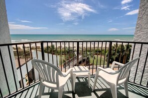 A balcony with a view of the beach, two white plastic chairs, and a railing. - Oceanfront King Room + Beach Access + Dog Friendly (Myrtle Beach)