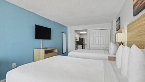 A hotel room with two beds, a TV, a desk, and a door leading to a bathroom. - Oceanfront Two Queen Room + Beach + Dog Friendly (Myrtle Beach)