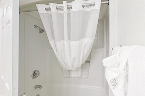 A bathroom with a shower curtain, a towel rack, and a white towel.