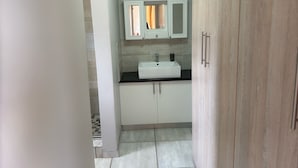 Une salle de bain avec un lavabo blanc, un miroir au-dessus et une porte en bois.