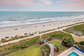A beach view with a pool, beach chairs, umbrellas, and a lifeguard tower. - Oceanfront | Kitchen | Dog Friendly | Pools&HotTub (Myrtle Beach)
