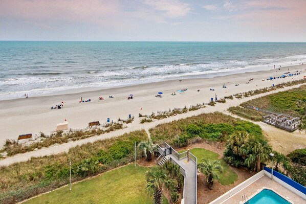 A beach view with a pool, beach chairs, umbrellas, and a lifeguard tower. - Oceanfront Two Queen Room + Beach + Dog Friendly (Myrtle Beach)