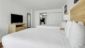 Una habitación de hotel con una cama grande, un televisor sobre un soporte de madera, un armario y una puerta que da al baño.