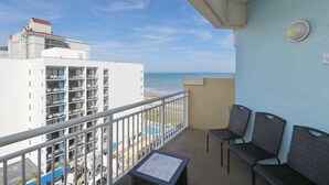 Ein Balkon mit Blick auf den Strand, einen Pool und ein Gebäude mit mehreren Balkonen.