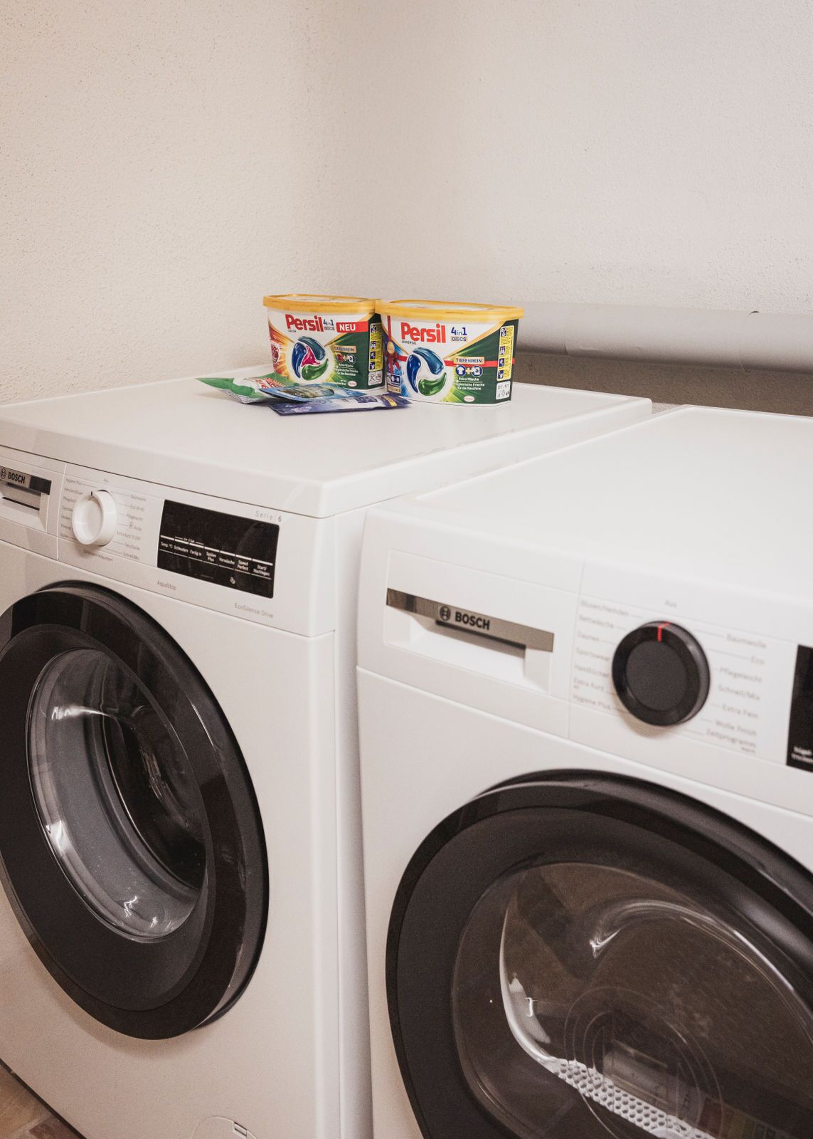 Two white Bosch washing machines with Persil detergent boxes on top.