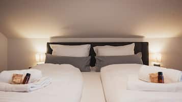 Ein Hotelzimmer mit zwei Betten, jeweils mit Kissen und Handtuch.