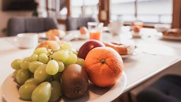 Une table de petit-déjeuner avec des fruits et un verre de jus d’orange.