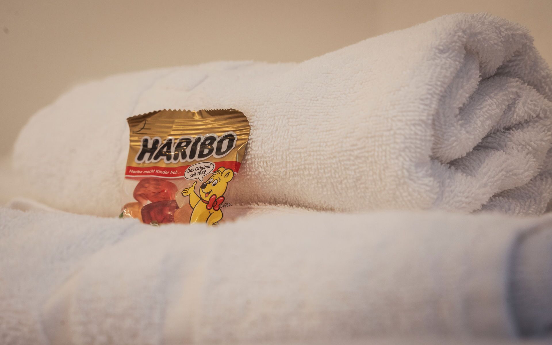 Ein gefaltetes weißes Handtuch mit einer Haribo-Schokoriegelverpackung darauf.