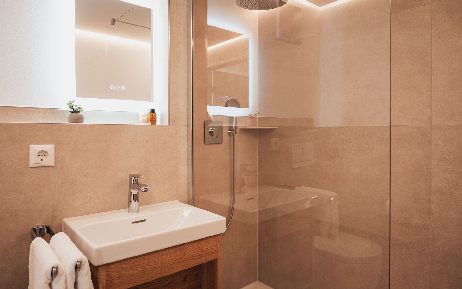 A modern bathroom with a glass-enclosed shower, a white sink, and a mirror above the sink.