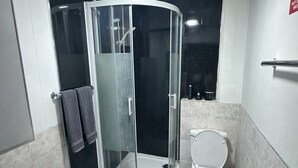 Ein Badezimmer mit einer Duschkabine, einer Toilette und einem Waschbecken.