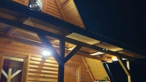 A wooden cabin with a pitched roof, a balcony, and a window.