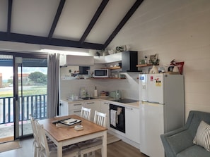 A compact kitchen with a dining table, chairs, a microwave, a refrigerator, and a small oven.