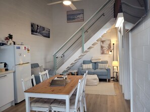 A compact living space with a kitchen, dining area, and a staircase leading to an upper level.