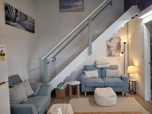 Una sala de estar con una escalera, un sofá, una mesita redonda y una lámpara.