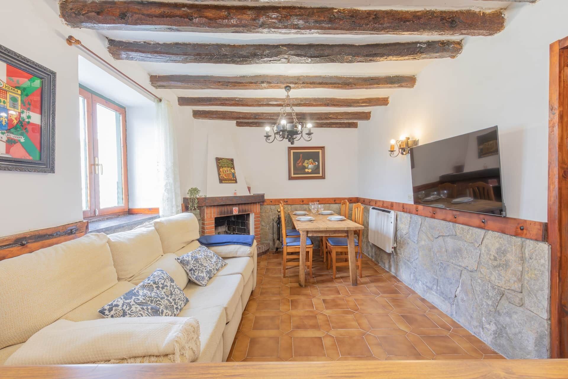 Een gezellige woonkamer met een bank, een eettafel en een open haard.