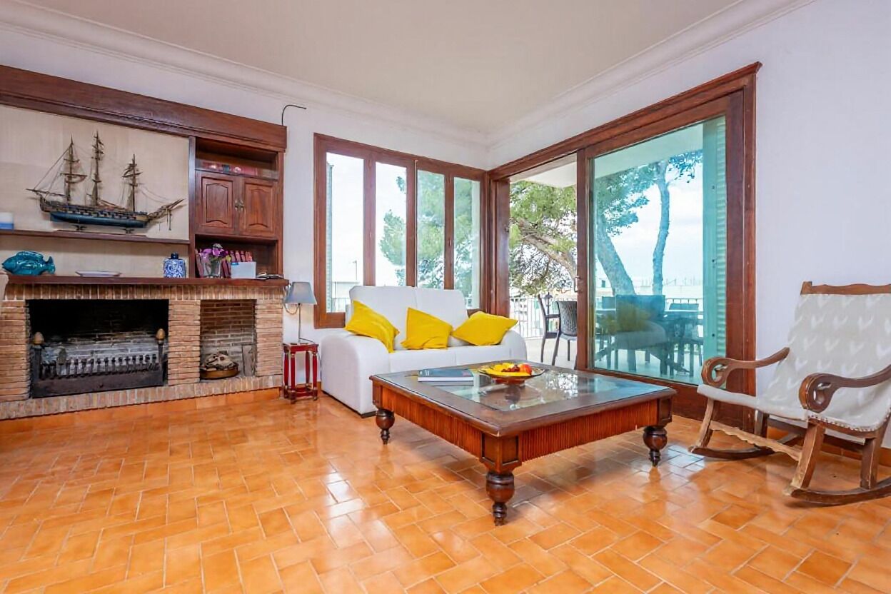 A living room with a fireplace, a white sofa with yellow pillows, a wooden coffee table, and a rocking chair.