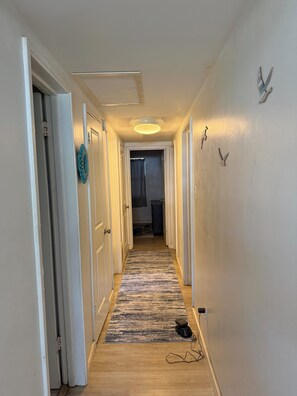 A narrow hallway with white walls, a patterned rug, and a ceiling light fixture. - 3-bedroom house in enchanting Fort Walton Beach with AC (Fort Walton Beach)