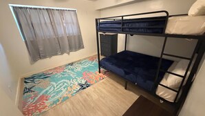 A bunk bed with a blue mattress, a small dresser, a window with curtains, and a patterned rug. - 3-bedroom house in enchanting Fort Walton Beach with AC (Fort Walton Beach)