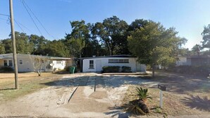 A residential area with a white house, a driveway, and a palm tree. - 3-bedroom house in enchanting Fort Walton Beach with AC (Fort Walton Beach)