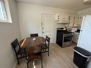 A compact kitchen with a round wooden table, two chairs, a stove, a microwave, and a refrigerator. - 3-bedroom house in enchanting Fort Walton Beach with AC (Fort Walton Beach)